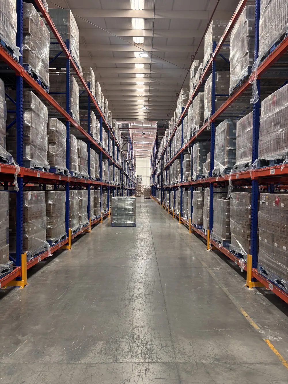 Pasillo de racks selectivos cargados con tarimas en un almacén
